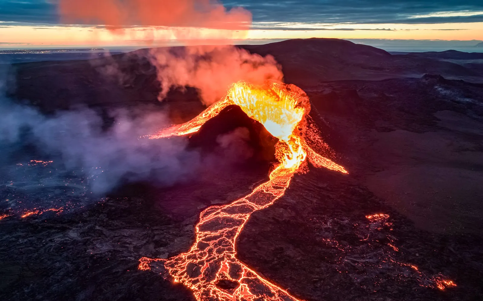 Ein Spalteneruptionsausbruch auf der Reykjanes-Halbinsel, fotografiert aus einem Hubschrauber, Lava glüht gegen schwarzes Gestein
