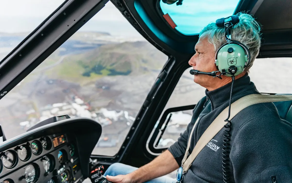 A helicopter pilot at the controls over Icelandic terrain