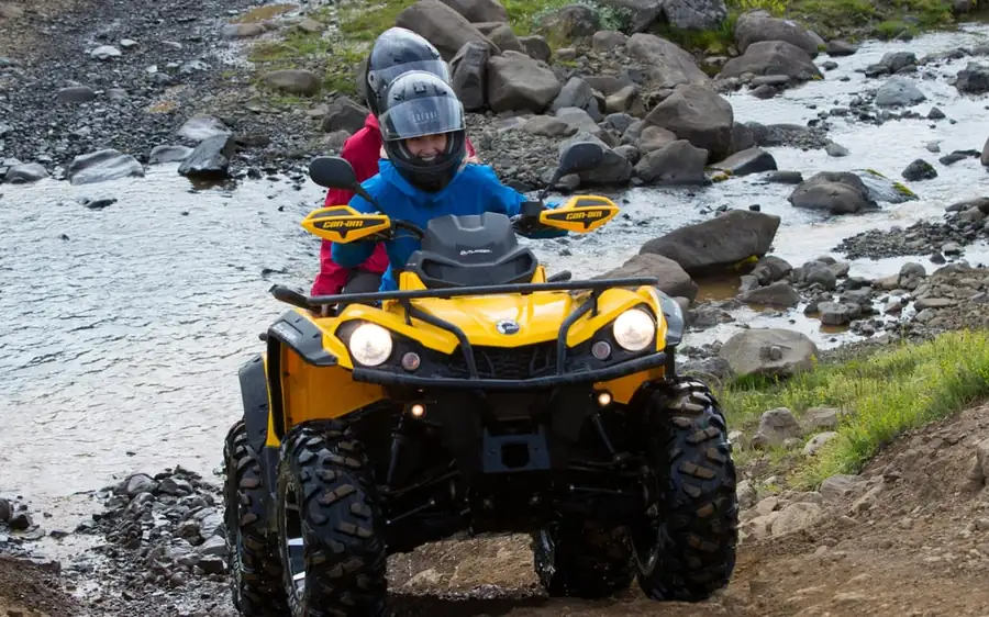 Two riders on quad bikes on a black gravel track in Iceland